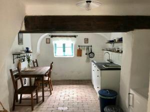 a kitchen and dining room with a table and a window at Káli Kerted Vendégházak Karolin néni háza in Monoszló