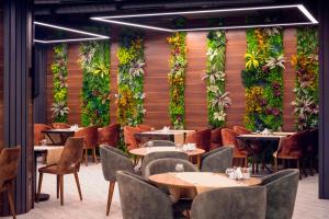 a restaurant with tables and chairs and plants on the wall at Novel Centre Point Hotel in Famagusta