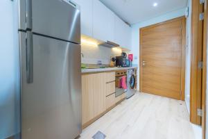 a kitchen with a stainless steel refrigerator and wooden cabinets at Cozy Studio In front of Metro Stn - Access to Gym & Pool - BRC in Dubai