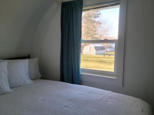 a bedroom with a bed and a window with a barn at Cozy Quonset Hut On Maple Lake in Paw Paw