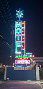 a sign for a motel with neon signs at night at Walden Motel in Las Vegas