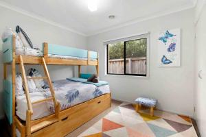 ein Kinderschlafzimmer mit Etagenbetten und einem Fenster in der Unterkunft Corymbia Barwon Heads Modern Family Getaway! in Barwon Heads