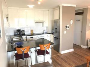 a kitchen with a counter and three chairs in it at Belle View @ Knysna Quays in Knysna