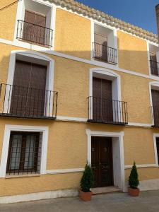 a yellow building with balconies and a door at Casa Rural Casa Sagasta in Elche de la Sierra