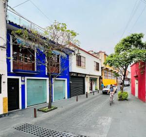 a person riding a bike down a street with buildings at Hotel Casa Frida in Cuernavaca