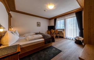 Un dormitorio con una cama grande y un escritorio. en Apartments Sunela, en Selva di Val Gardena