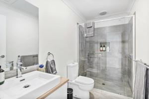 a bathroom with a shower and a sink and a toilet at CASA EMEC- luxury, aircon, walk to the shops and beach! Outdoor shower and garage parking in Ocean Grove