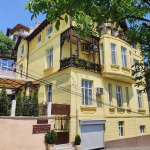 a yellow building with a balcony on top of it at Guest House Gurkov in Veliko Tŭrnovo