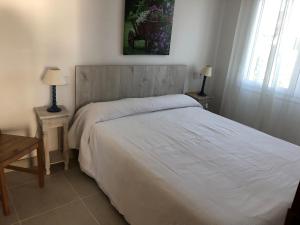 um quarto com uma cama branca com 2 mesas e 2 candeeiros em Apartamentos Miradores em Miami Platja