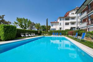 a swimming pool with chairs and a building at Apartments Rainer - Front Lake in Bardolino