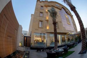 un bâtiment avec des tables et des palmiers devant lui dans l'établissement Awj Jazan Suites Hotels, à Jazan