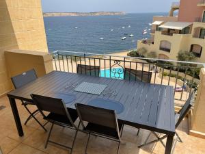 a table on a balcony with a view of the ocean at Seaview Family Apartment, Pool, Easy Access to the Sea, Near Mellieħa Bay in Mellieħa