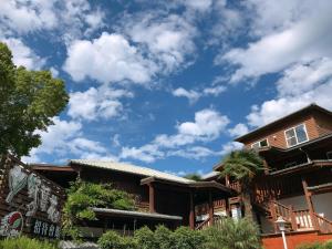 a house with a blue sky with clouds at Ye Jiang Hua Homestay in Meishan
