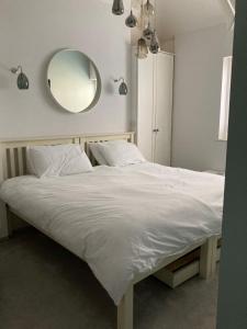 a bedroom with a large white bed with a mirror at Kitchener Cottage Swanage very close to beach in Swanage