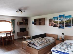 a bedroom with a bed and a table and a desk at Appartamenti Soravia in Sappada