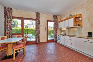 a kitchen with white cabinets and a table and chairs at Apartments Rainer - Front Lake in Bardolino