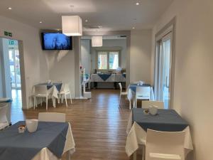 a dining room with tables and chairs and a television at Acqua & Sale Hotel in Cervia