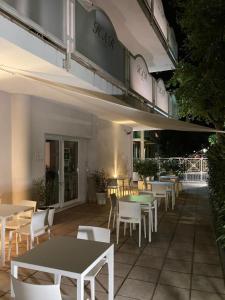 a restaurant with tables and white chairs and avisor at Acqua & Sale Hotel in Cervia