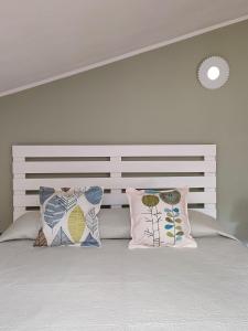 um quarto com uma cabeceira branca e almofadas numa cama em La_casa_di_ Willy em Canai