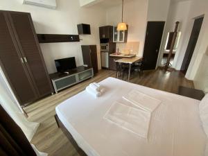 a bedroom with a large white bed and a kitchen at Apartment In Batumi MGZAVREBI in Batumi