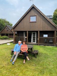 a man and woman sitting on a picnic table in front of a building at La Fortuna Lodges in Stirling