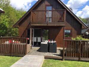 a large wooden house with a deck with a table at La Fortuna Lodges in Stirling