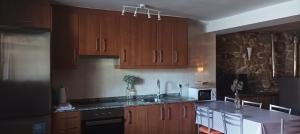 a kitchen with wooden cabinets and a sink and a microwave at Casa do Xurés in Maus de Salas