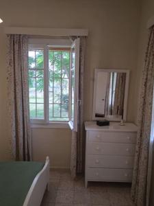 1 dormitorio con tocador, espejo y ventana en Authentic Country House in Zakynthos, en Ambelókipoi