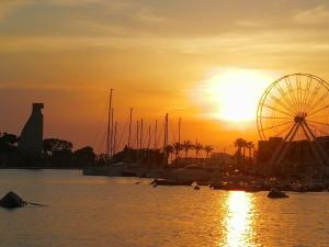 una noria y barcos en un puerto al atardecer en CIVICO 63, en Brindisi