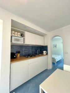 a kitchen with white cabinets and a microwave and a table at Attico Panoramico in Anacapri