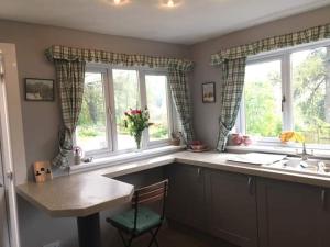 a kitchen with a table and two windows and a sink at Pinetree Cottage, dog friendly, Holiday let, Callander Invertrossachs in Callander