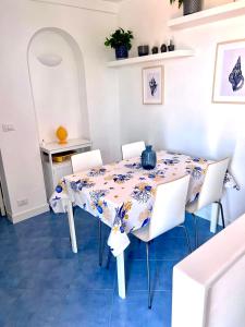 a dining room with a table and white chairs at Attico Panoramico in Anacapri