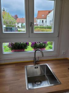 - un évier de cuisine devant deux fenêtres dans l'établissement Haus mit stilvoller Ferienwohnung und Tiny House nahe Ammersee für 2-6 Personen, à Geltendorf