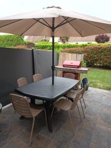 una mesa y sillas con una sombrilla en el patio en Chasseport, en Saint-Saturnin
