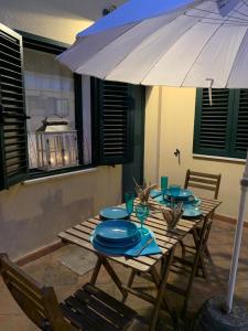 Una mesa de madera con platos azules y una sombrilla. en Raffinata taverna con camino, en Cala Liberotto 9 fotos más