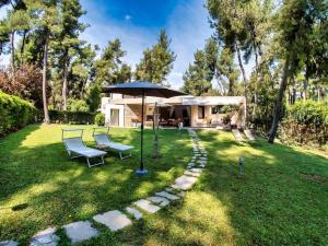 einen Garten mit zwei Stühlen und einem Sonnenschirm in der Unterkunft Sani Villa Lili 7 in Sani Beach