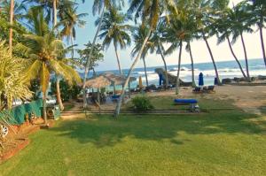 een uitzicht op een strand met palmbomen en de oceaan bij Sri Gemunu Beach Resort in Unawatuna