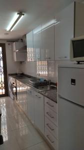 apartamento Anais في سالو: مطبخ فيه دواليب بيضاء وثلاجة بيضاء