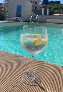 un bicchiere di vino seduto su un tavolo accanto alla piscina di Valenti rooms & relax a Villaggio Mosè
