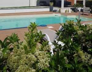 a swimming pool with two white chairs and some plants at Valenti rooms & relax in Villaggio Mosè
