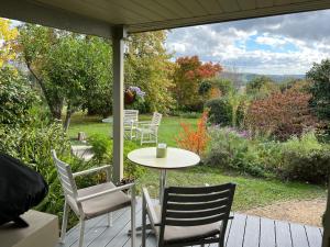 a table and chairs on a porch with a view of a garden at The Little House on The Hill in Badger Creek