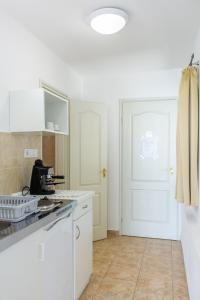 a kitchen with white cabinets and a white door at Wesselényi Strand apartmanok in Balatonalmádi