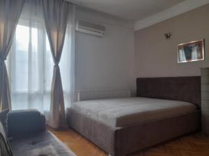 een slaapkamer met een bed en een groot raam bij Mario Sunce Apartmani in Niš