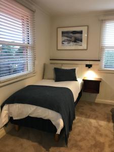 a bedroom with a bed with a black blanket and two windows at Silwood Apartment fully self contained with Kitchen and Laundry in Devonport