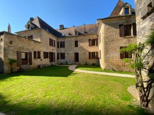 a large stone building with a grass yard at Appartement de caractère à la Roque-Gageac in La Roque-Gageac