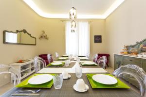 uma sala de jantar com uma mesa longa com guardanapos verdes em Maecò Ortigia B&B em Siracusa