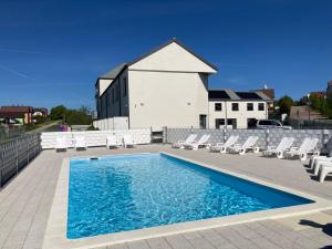a swimming pool with white chairs and a building at Sofia Domki Wakacyjne Dwupoziomowe in Jarosławiec