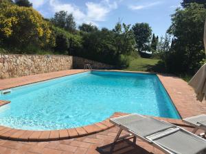 una piscina con 2 sillas y una pared de piedra en Viva House, en Montaione