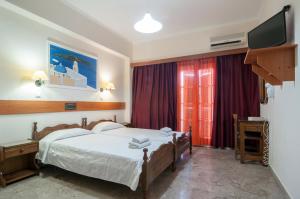 a hotel room with two beds and a television at Holiday Beach Resort Santorini in Perivolos