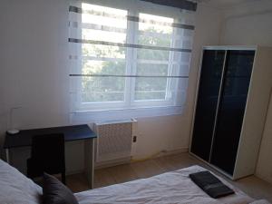 Schlafzimmer mit einem Bett, einem Schreibtisch und einem Fenster in der Unterkunft Grey Harmony Apartman in Debrecen